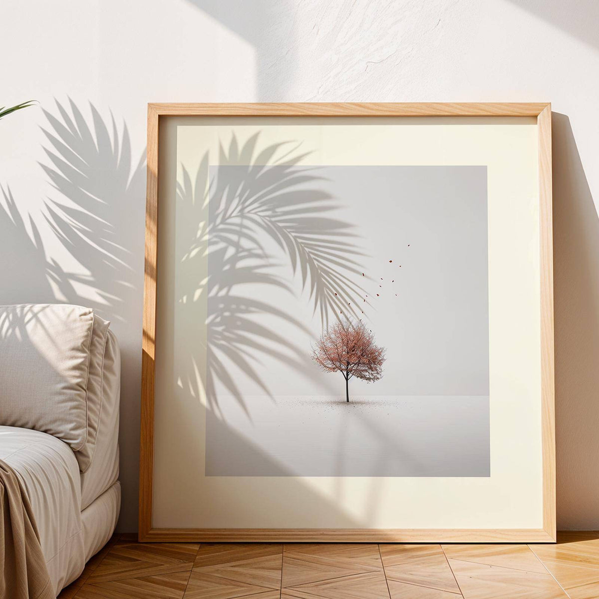 Framed Tree Wall Art of a minimalist single tree with falling leaves near a beige cushion