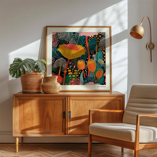 Floral prints for framing with abstract botanical pattern in bright colours leaning on a wooden sideboard beside a plant and beige armchair
