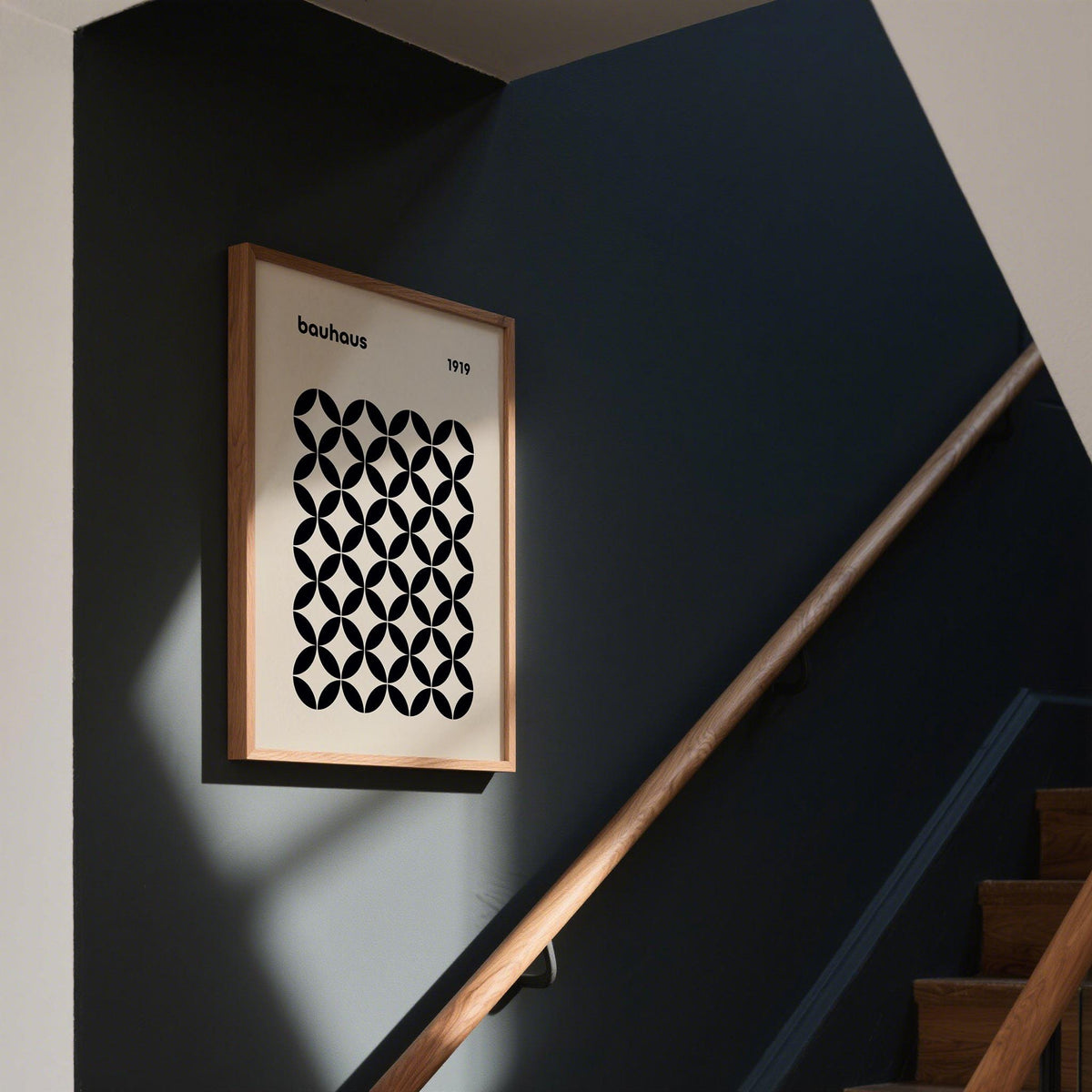 Mid Century Wall Print with black geometric grid hung on a dark wall above a wooden handrail of stairs