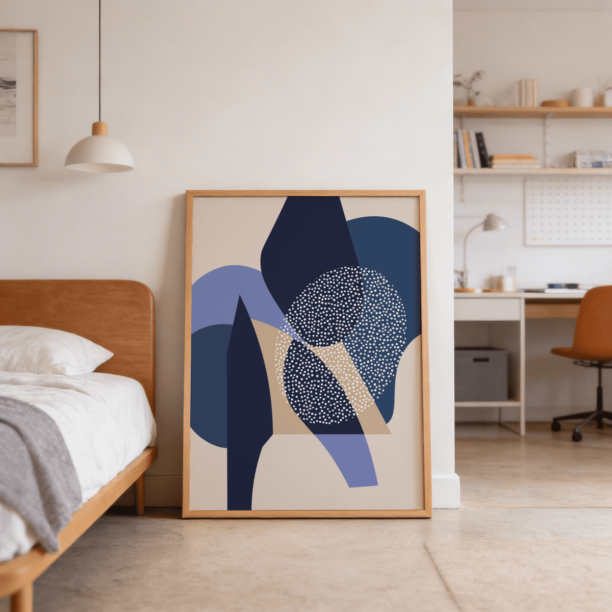 Print leaning on floor of blue abstract shapes in minimalist style next to bed in bedroom