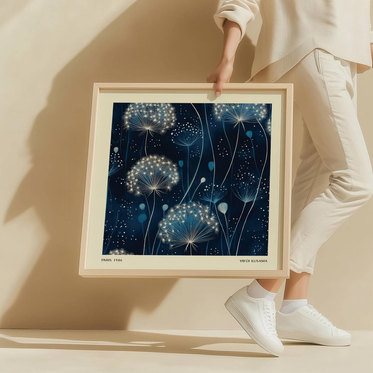 Blue art work of minimalist dandelion seed heads in white and blue held by person dressed in white