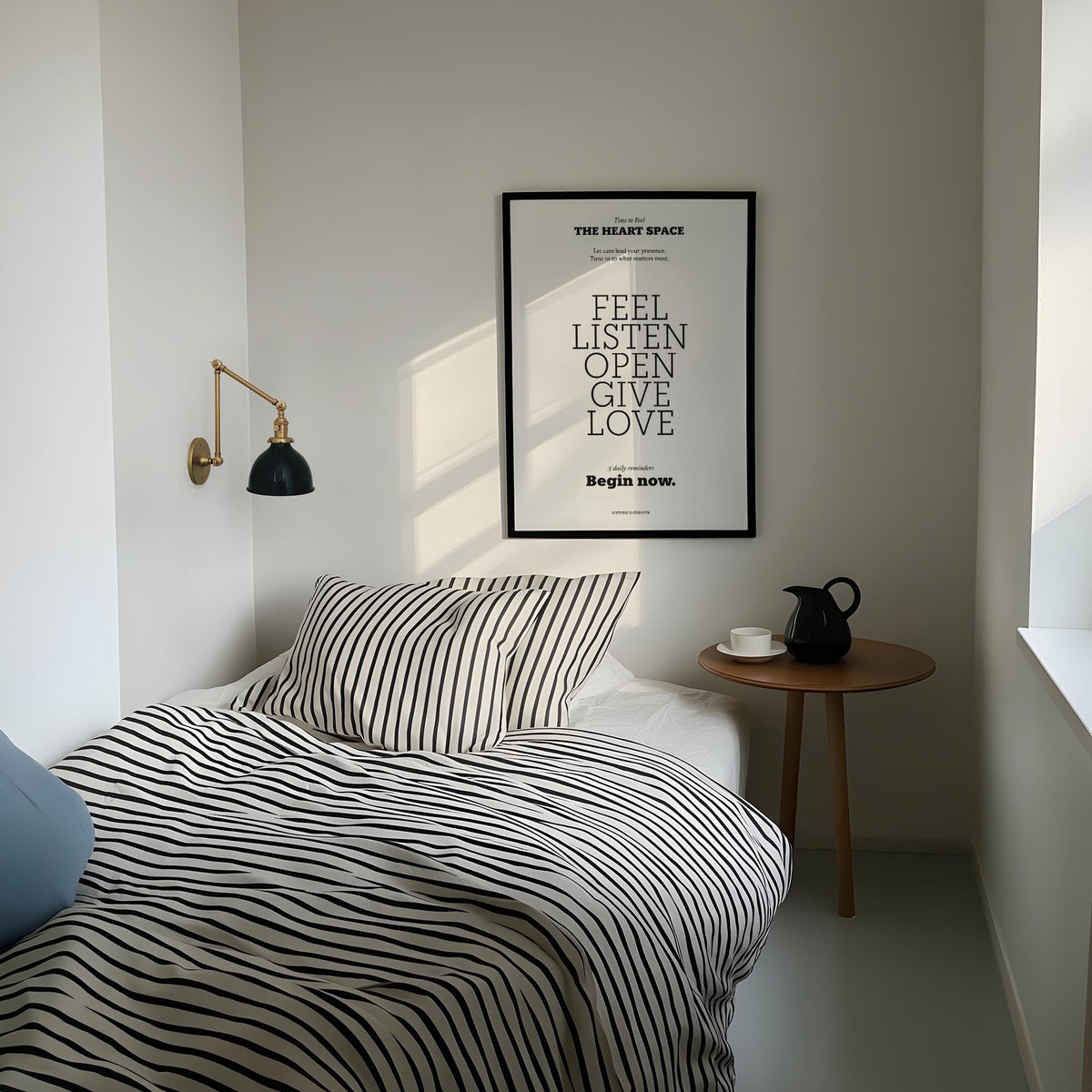 Bedroom wall decor quotes print with black frame and black and white striped bedding by a wooden side table