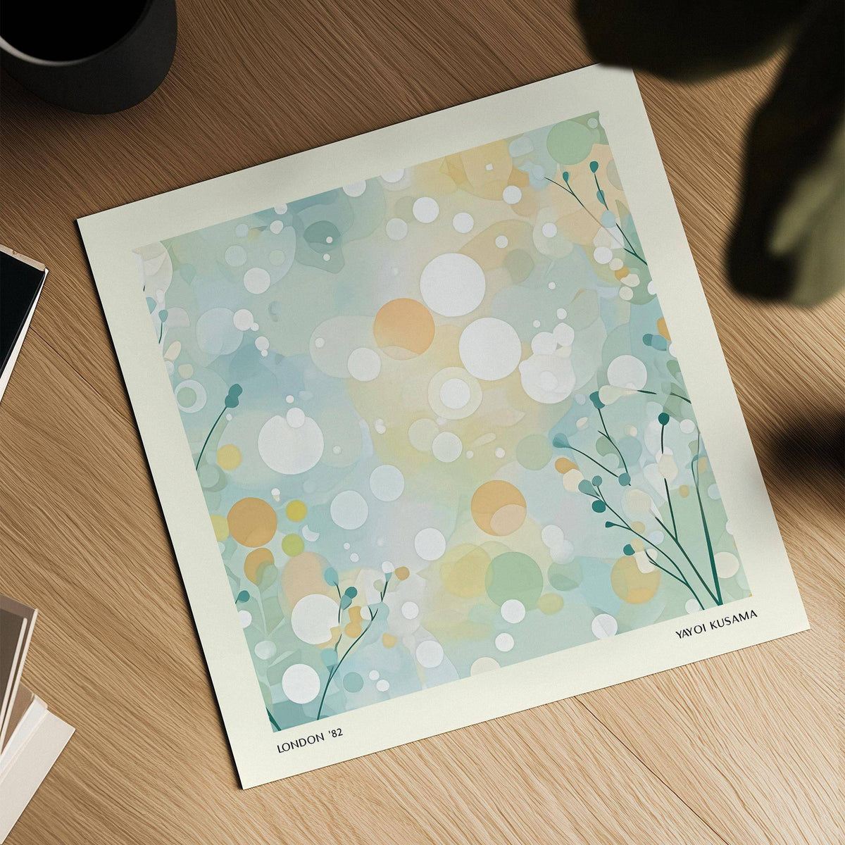 Abstract circles and dots in soft blue and orange hues on a print on a wooden surface with a plant leaf shadow