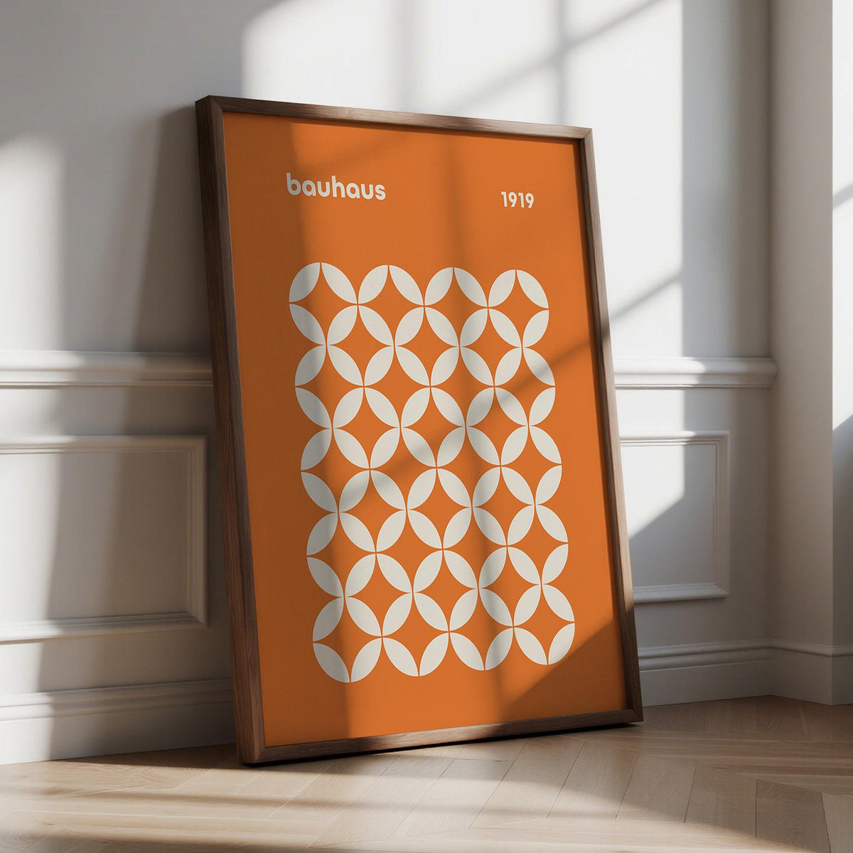 Framed Orange Poster with white bauhaus circle grid pattern leaning on floor with wall panel