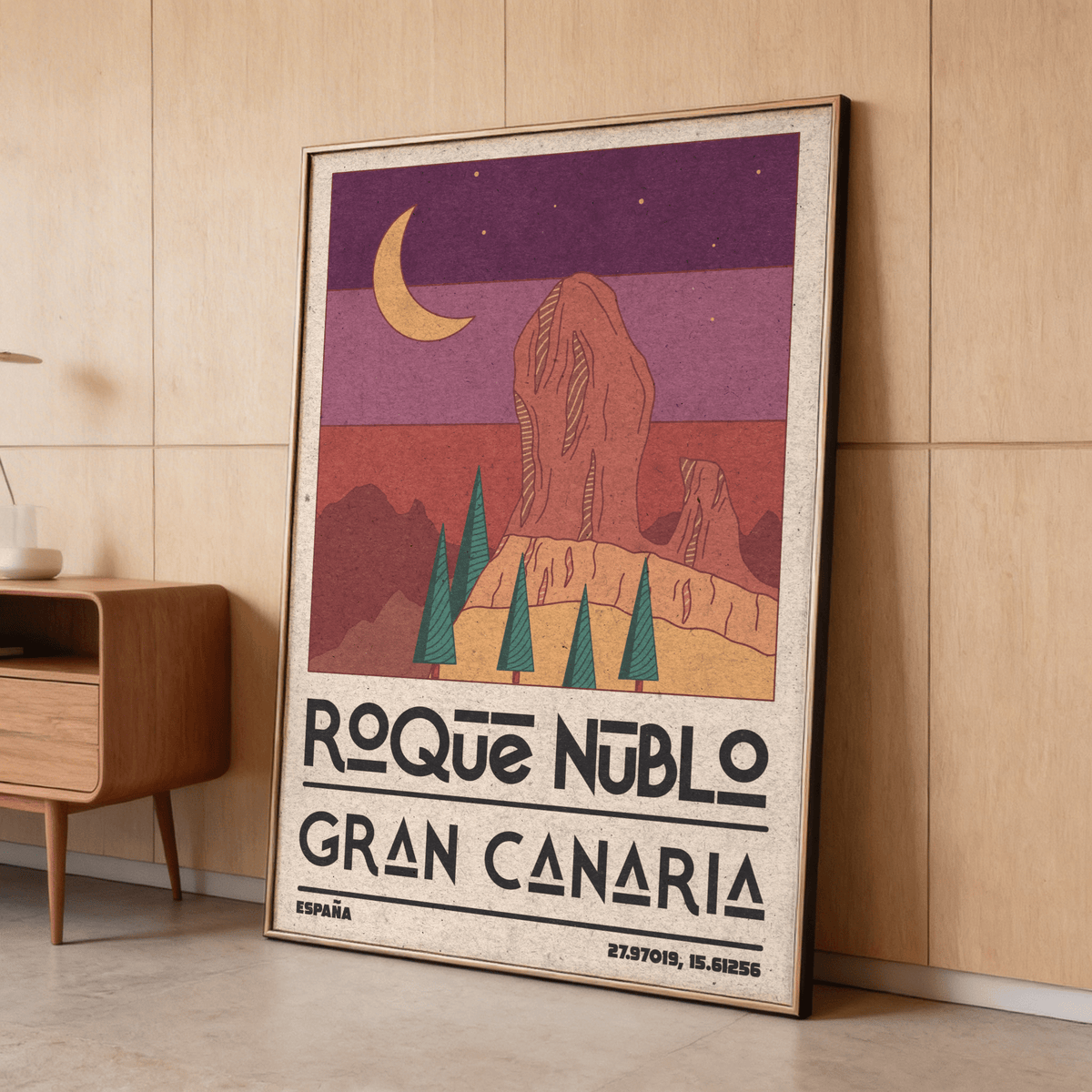 Framed Roque Nublo wall art with crescent moon retro illustration leaning against a wood panel wall by a cabinet