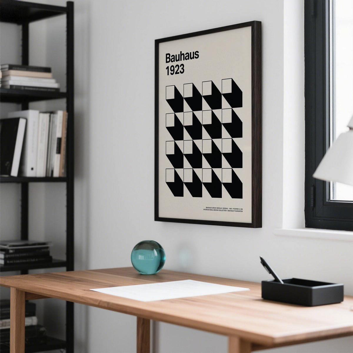 Office Space Poster wall art in black and white geometric shapes on a white wall above a wooden desk with a teal glass orb