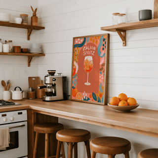Italian Spritz art print leaning on a kitchen counter with wooden stools and a bowl of oranges
