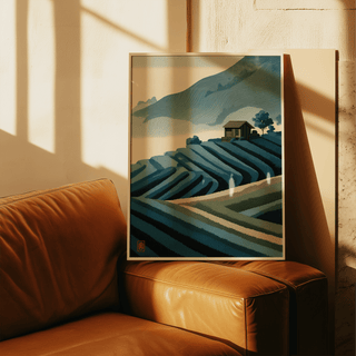 Print leaning on a leather sofa of a mountain tea plantation in blue and green tones with a small house
