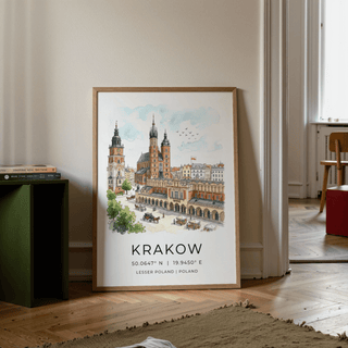 Krakow Cityscape wall art leaning on a wooden floor near books and a chair with light walls