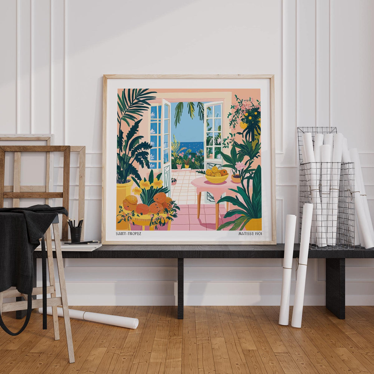 Coastal wall art with open doors, sea view, green plants and pink table leaning against wall