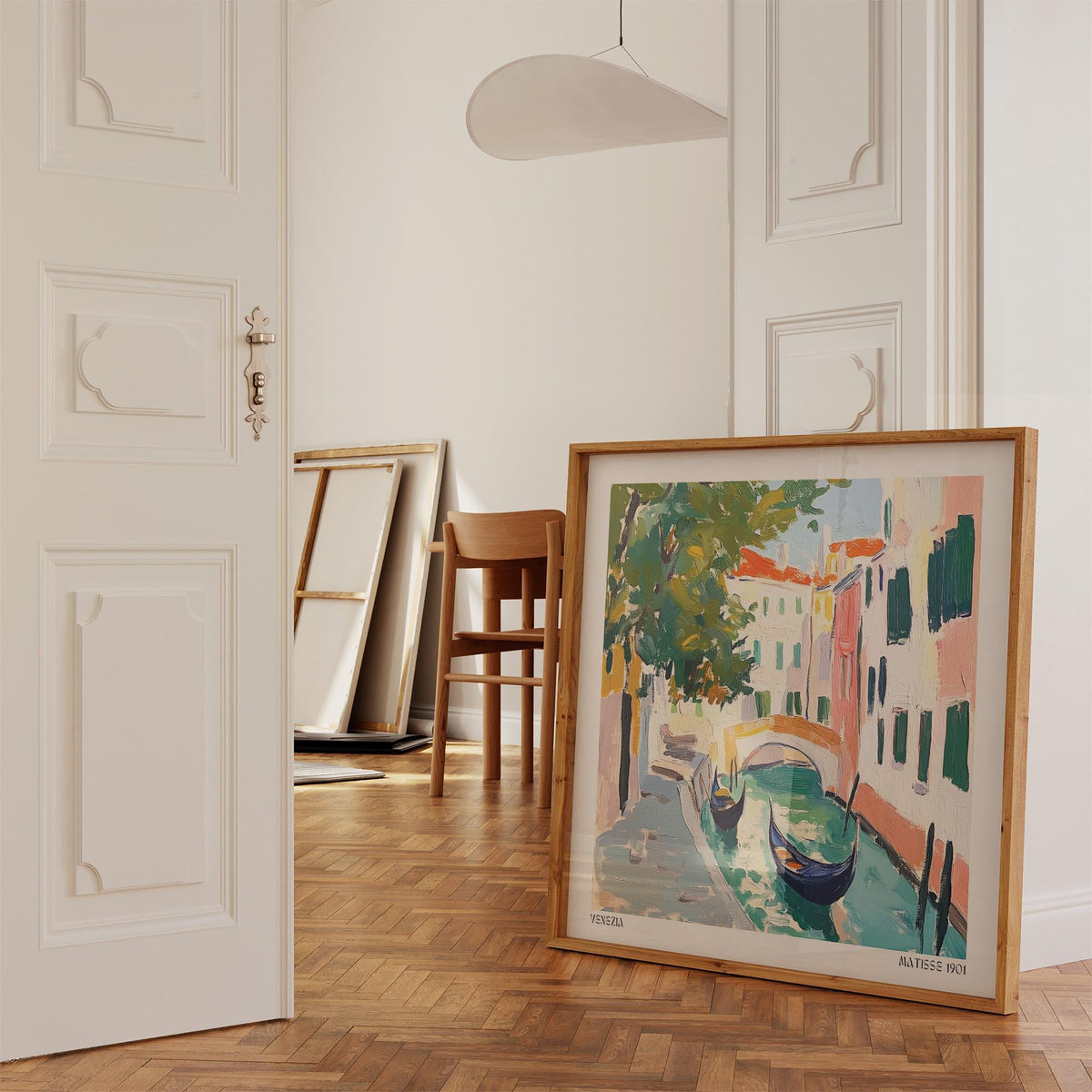 Venice wall art leaning on wooden floor in a doorway with a wooden chair in the background