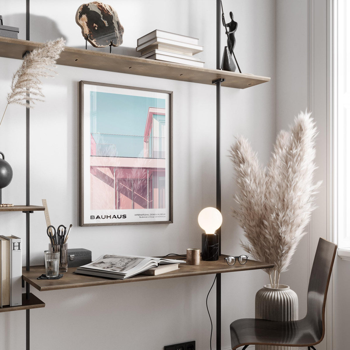 Bauhaus Style print on a wall showing a pink modern building facade in a neutral workspace with pampas grass