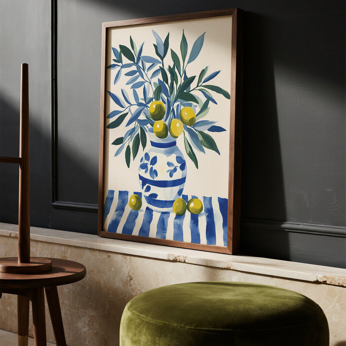 Olive Tree wall art of a vibrant olive branch in blue and green hues leaning on a stone shelf with a green velvet stool nearby