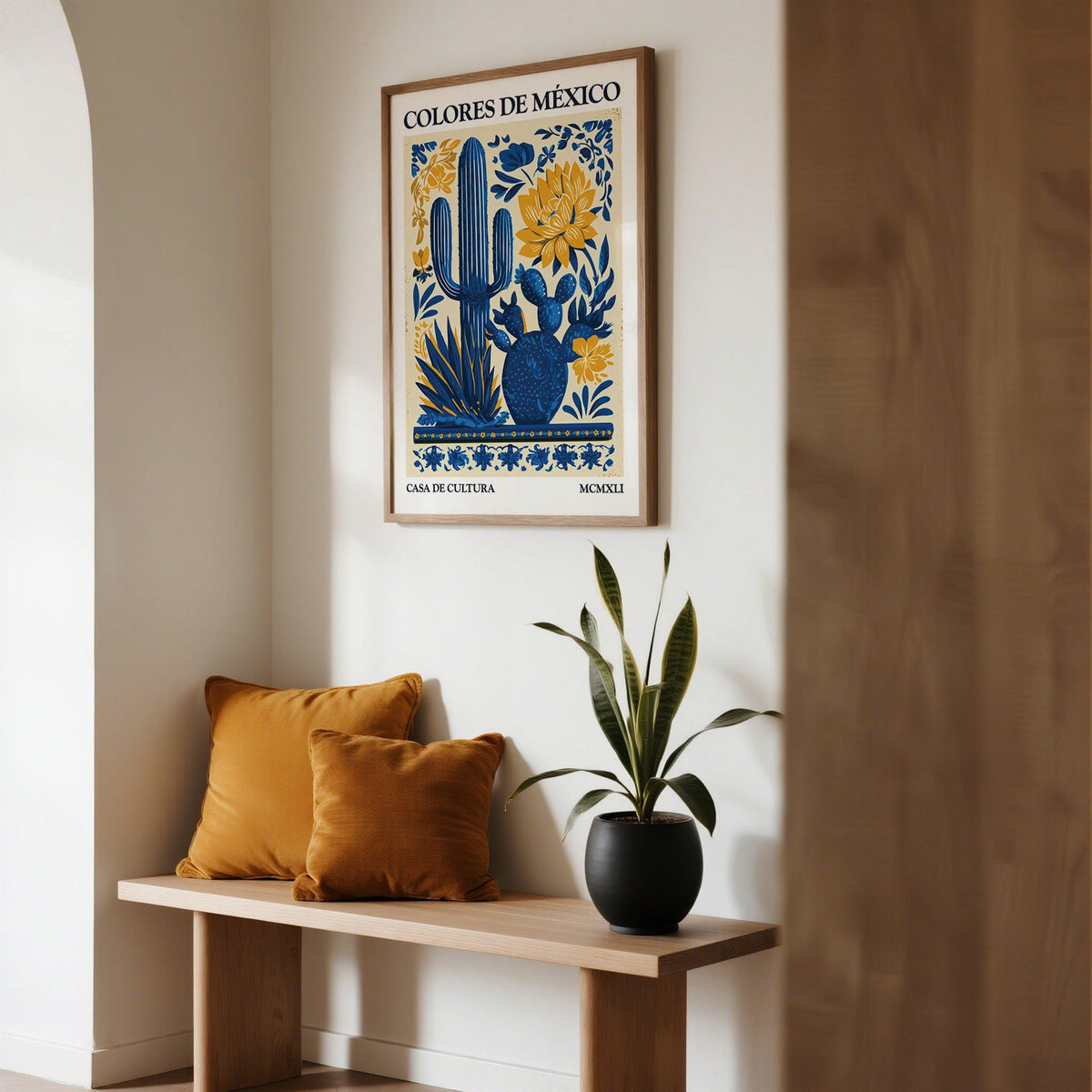 Mexican Folk Art print with blue agave and yellow flowers above a bench with orange cushions in a hallway