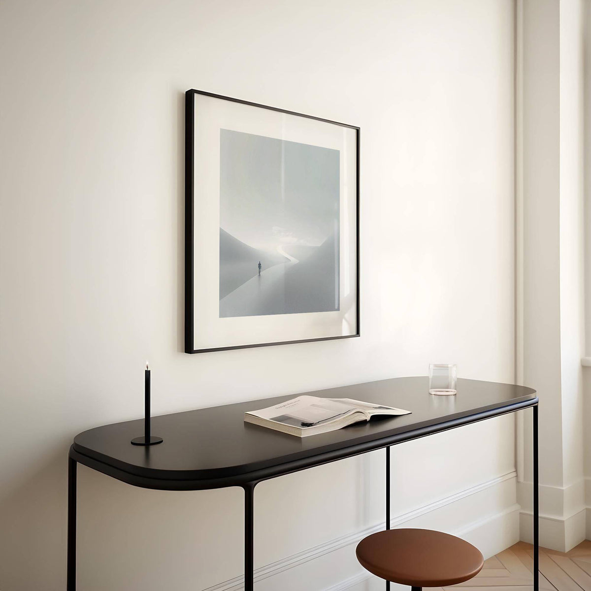 Gray and White Wall Art framed print close-up of a person on a winding path in muted greys above a black console table with a candlestick