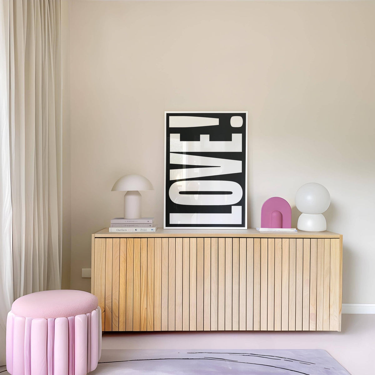 Print on a wall of LOVE typography in white on black above a sideboard with lamps and a pink stool