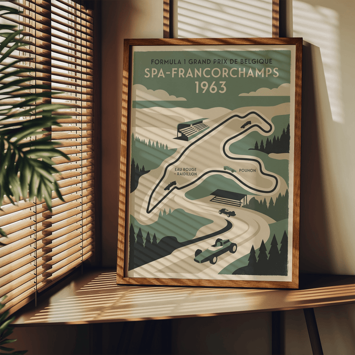 Framed Belgian Race Circuit Map Poster leaning on a wooden shelf with window blinds and a green plant nearby
