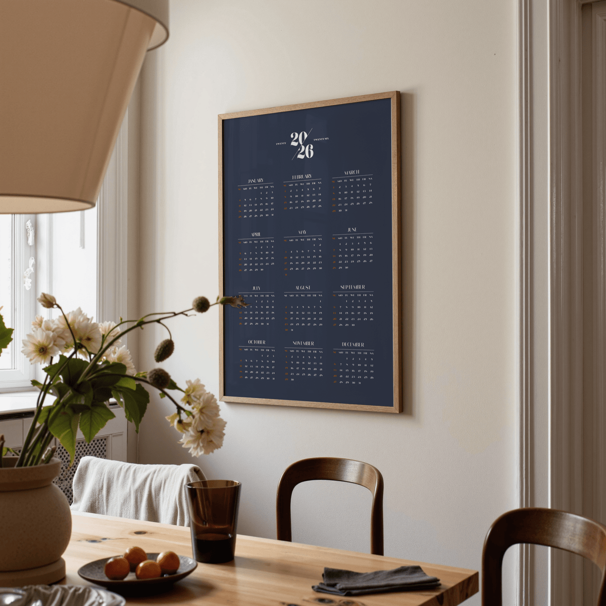 Minimalist Calendar print on a wall in a dining room with wooden chairs and a table lamp