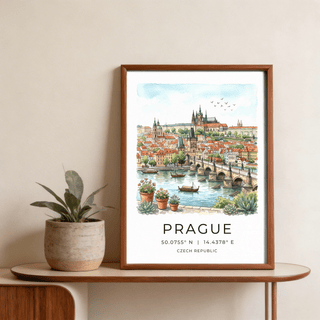 Framed Prague City Wall Art of watercolour Prague cityscape with blue sky and buildings on a shelf next to plant