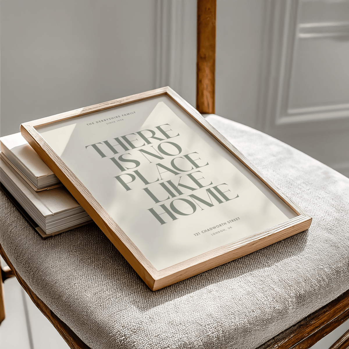 Framed No Place Like Home Print leaning on a chair with natural wooden frame and muted tones