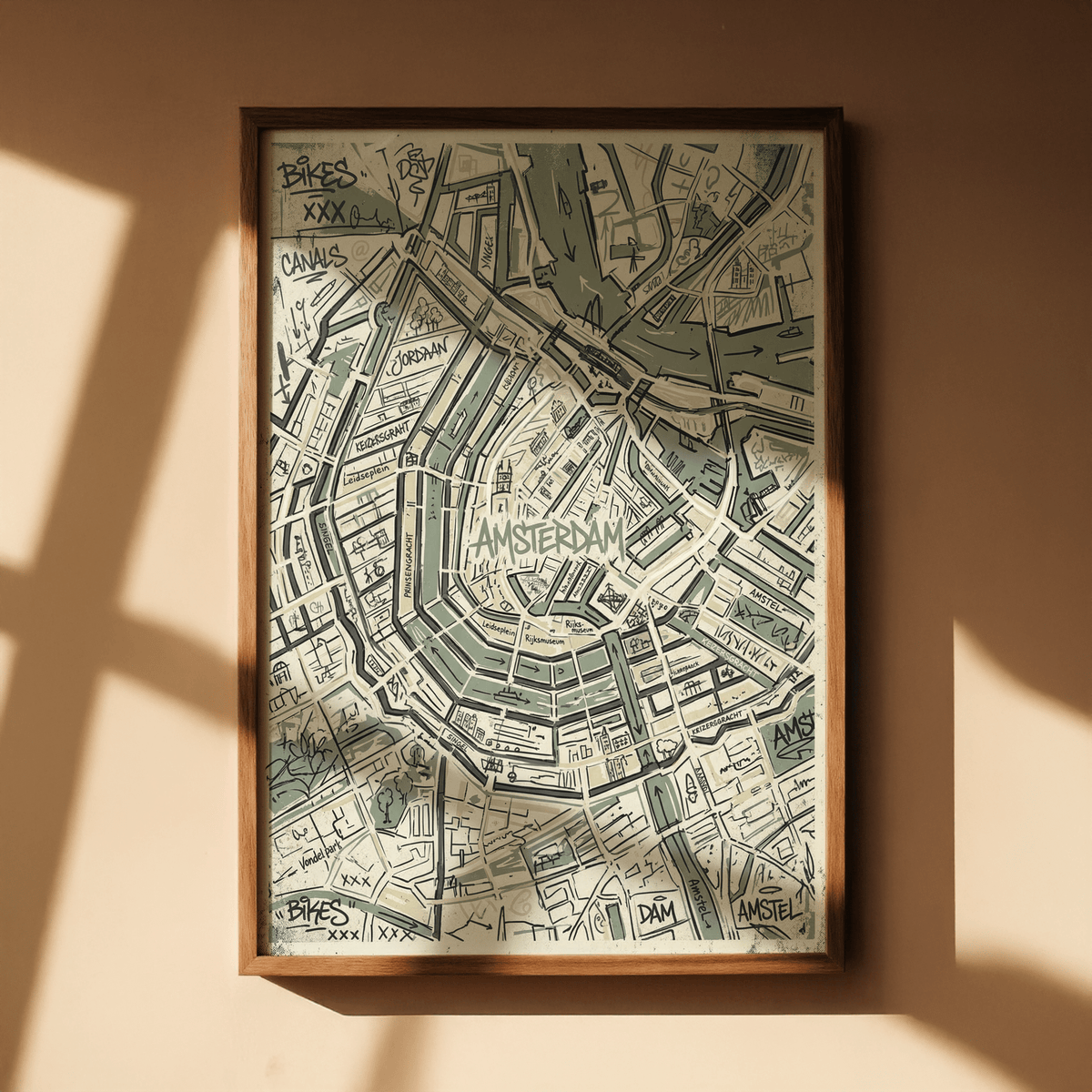 Framed Amsterdam map art print in green and beige tones with shadow on tan wall