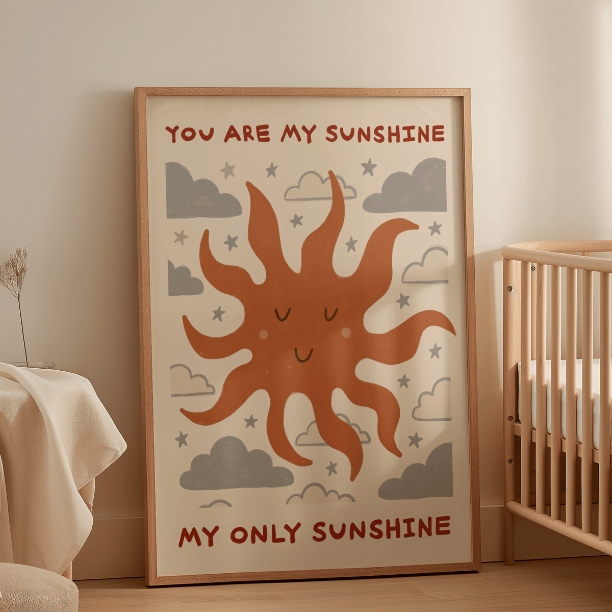 Sunshine quote wall art with a smiling orange sun and grey clouds leaning by a baby cot