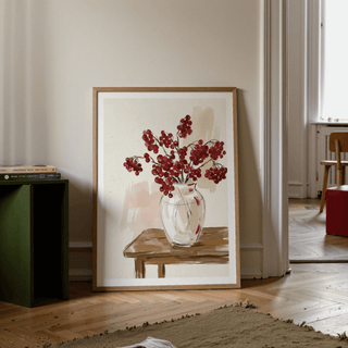Print leaning on floor showing red berries poster with watercolour style and wood table in a room