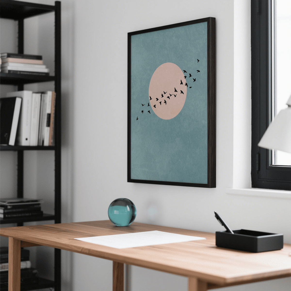 Wall Art Birds print with black birds on blue and pink background above a desk with glass paperweight