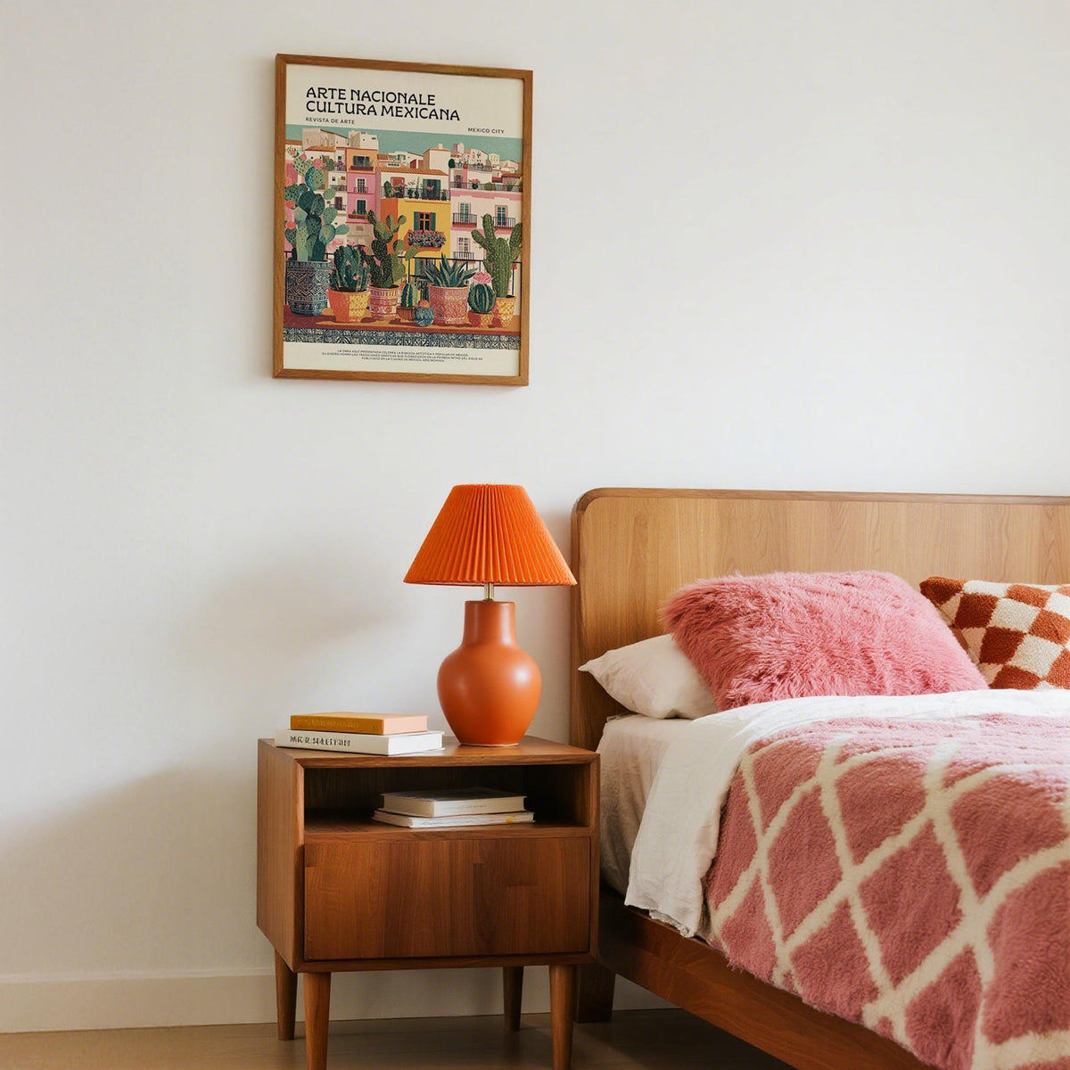 Latin American wall art of potted cacti and succulents above a mid-century bedside table with an orange lamp