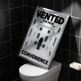 Print leaning on a toilet in a black tiled room with a minimalist design