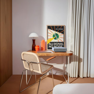 Vinyl Record Poster leaning on a wooden desk with a white lamp and orange vase in a softly lit room
