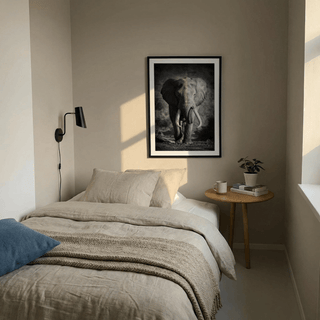 Print of lone elephant tusks in black and white above bed with beige bedding and side table