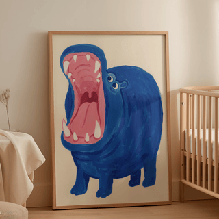 Blue Hippo Art Print leaning on the floor by a wooden baby cot in a softly lit nursery