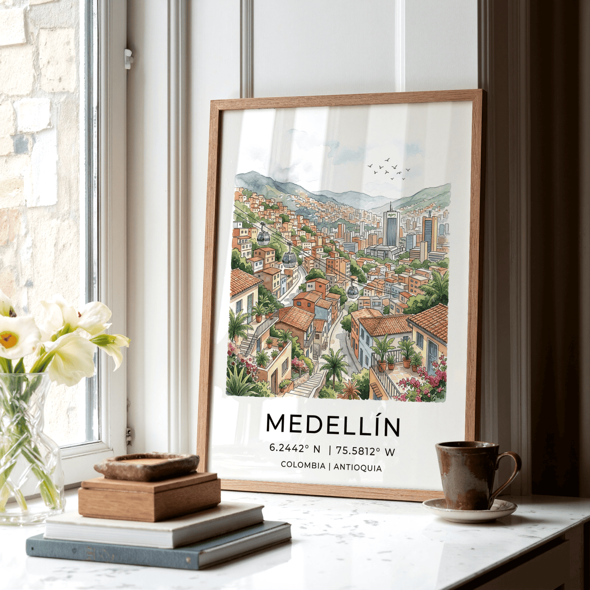Print leaning on a shelf of Medellin City Art Print showing a colourful hillside neighbourhood with a cup beside it