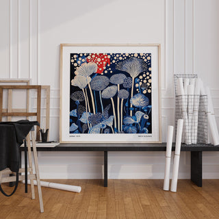 Red and Blue Art print with abstract mushroom shapes in red and blue leaning on a black bench near rolled posters