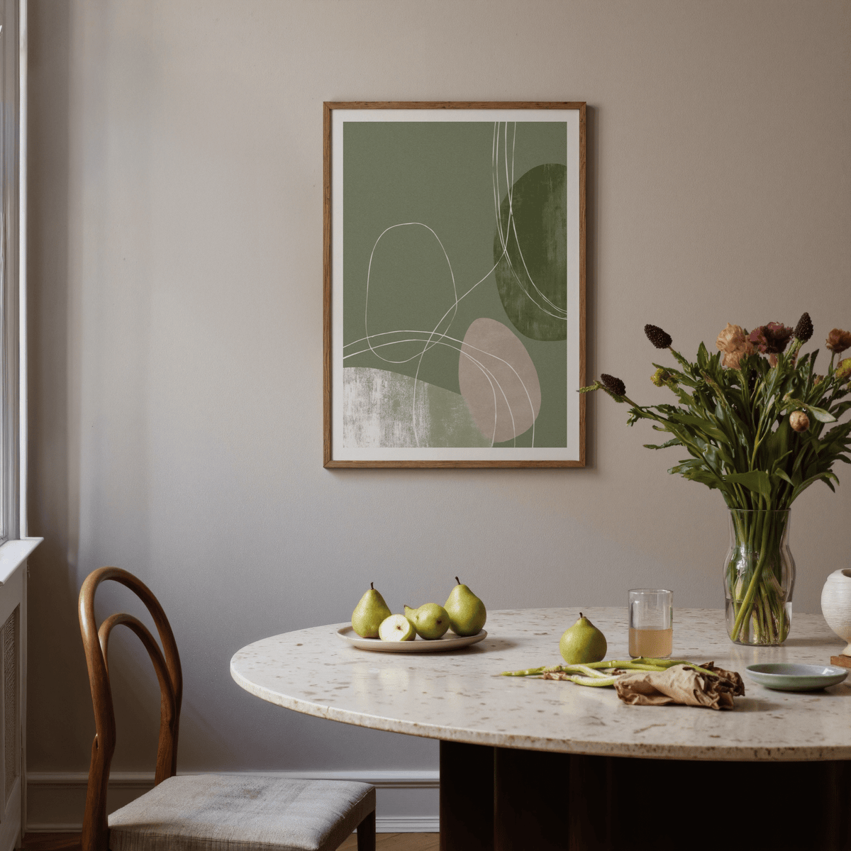 Minimalist Line Art framed print of abstract shapes in green and beige in a dining room with a round table and pears