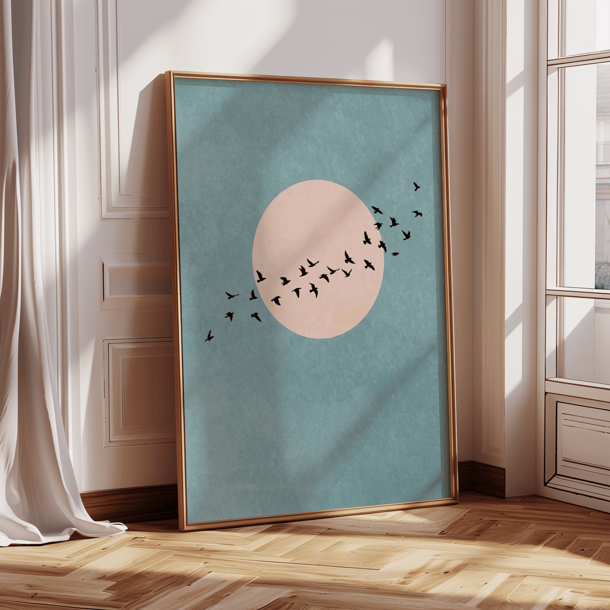 Print leaning on a floor showing a flock of birds in flight against a pink circle on a blue background in natural light