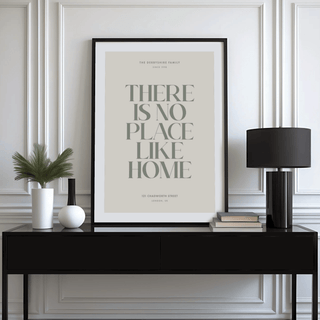 Print leaning on a black sideboard of a minimalist typographic quote in green and grey with a black lamp and books