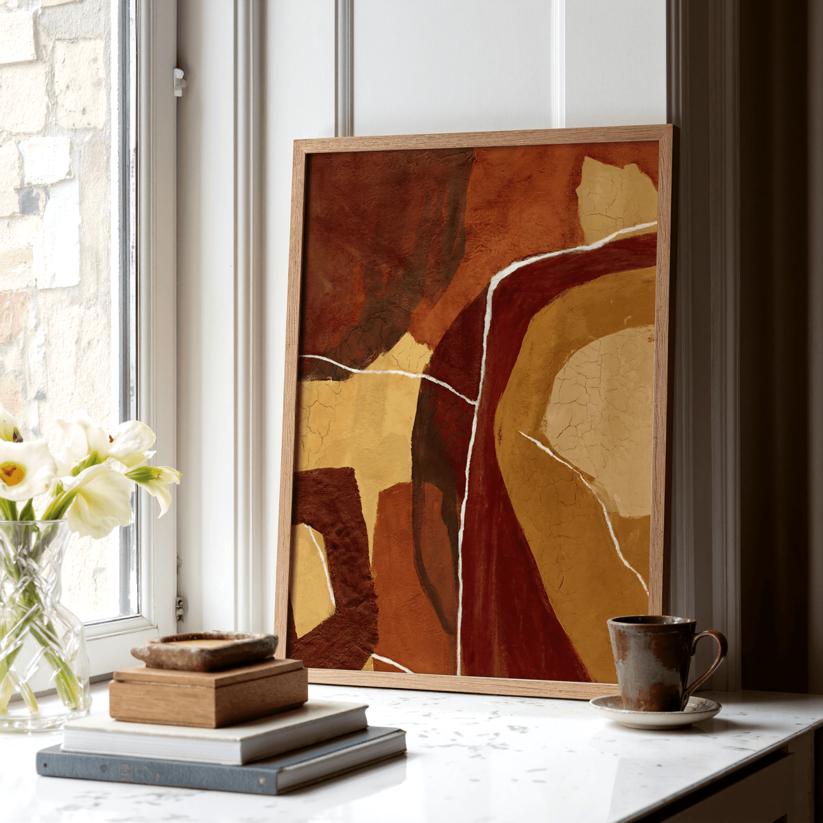 Abstract Earth Tones Print leaning on a windowsill with earth tone shapes and a brown mug nearby