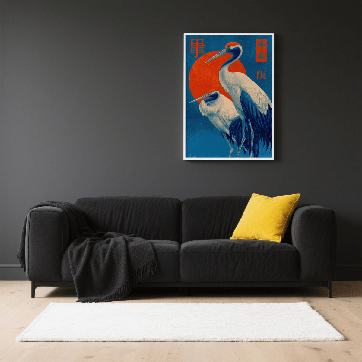 Cranes art print with white and dark blue birds against a red sun above a black sofa in a living room