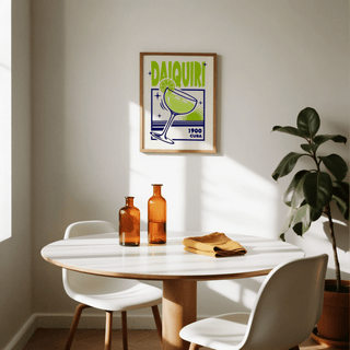 Daiquiri Art Print hanging above a dining table with orange glass bottles and a green plant