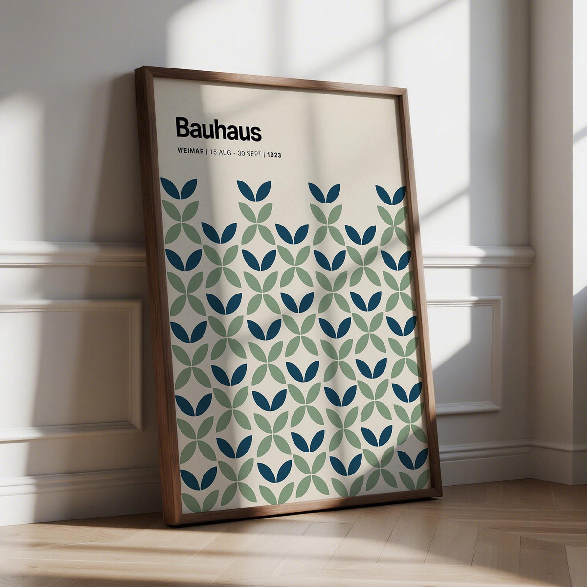 Framed Blue and Green Wall Art with geometric leaf pattern leaning against a white wall