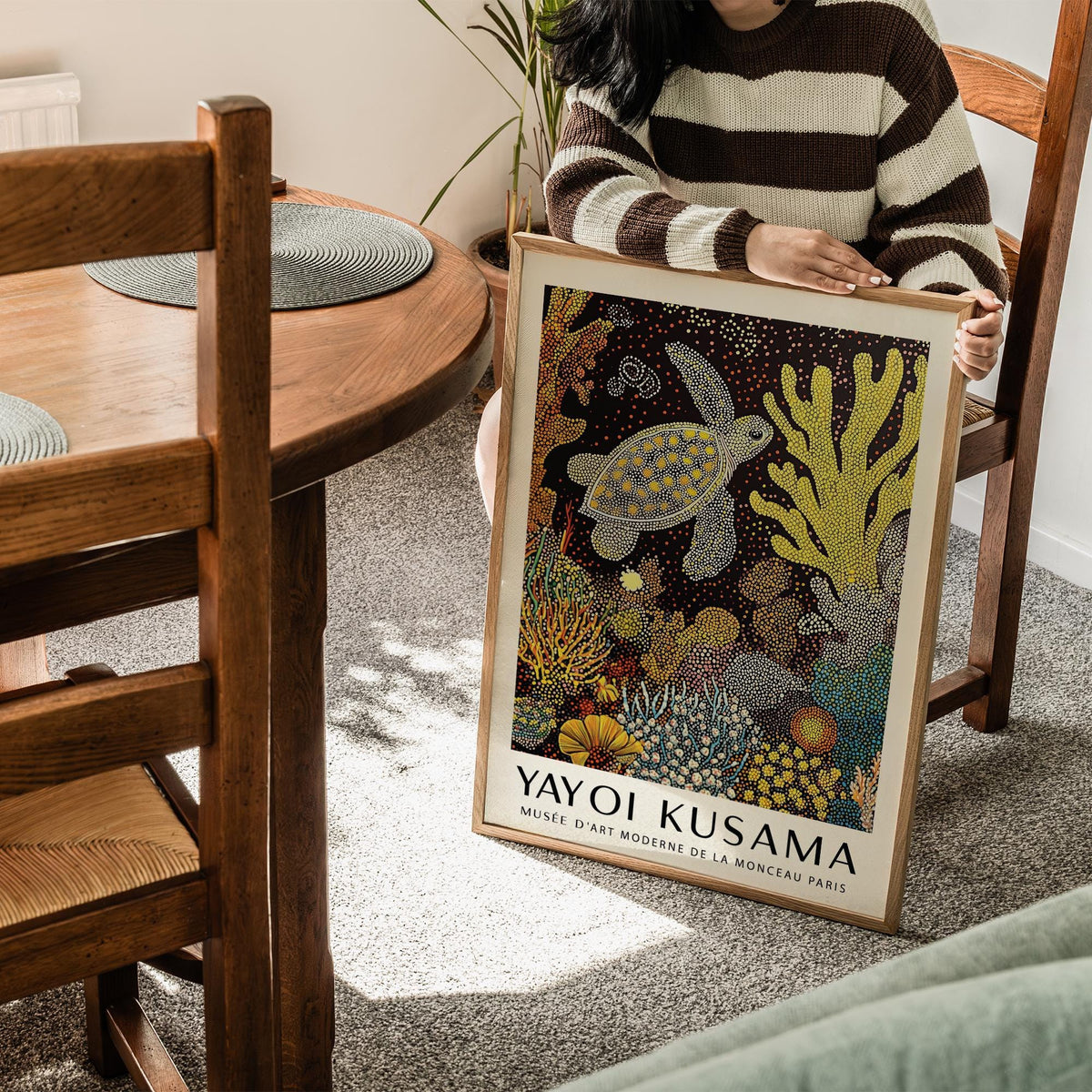 Framed sea turtle wall art held by person in striped jumper showing yellow and orange coral details