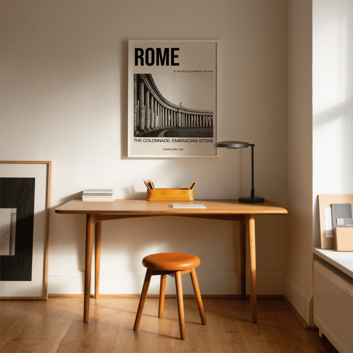 Colonnade Architecture Art Print framed print above a wooden desk with a lamp and orange stool in a minimalist room