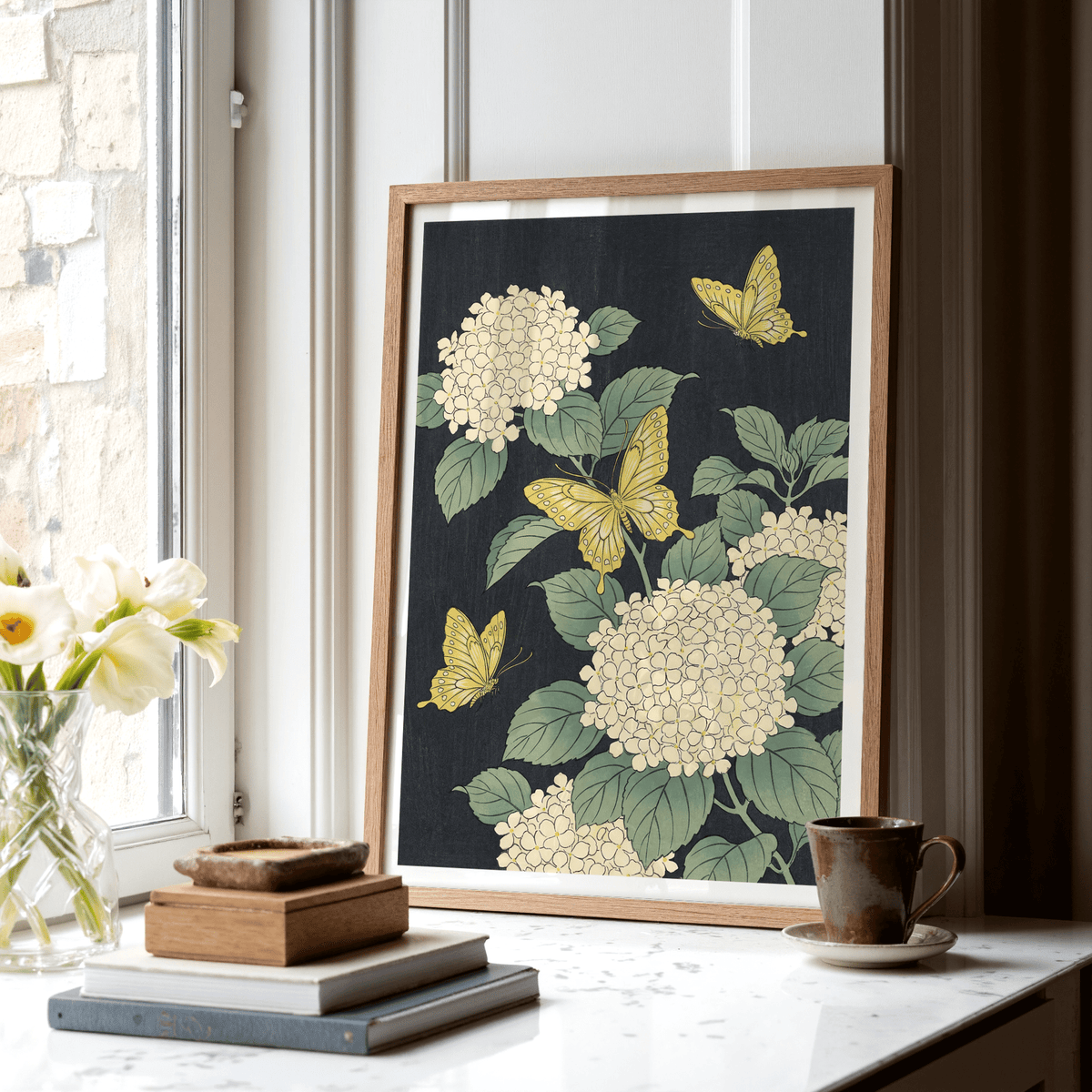 Vintage Butterfly Poster print leaning on a window sill with yellow butterflies and white hydrangea beside books and a cup