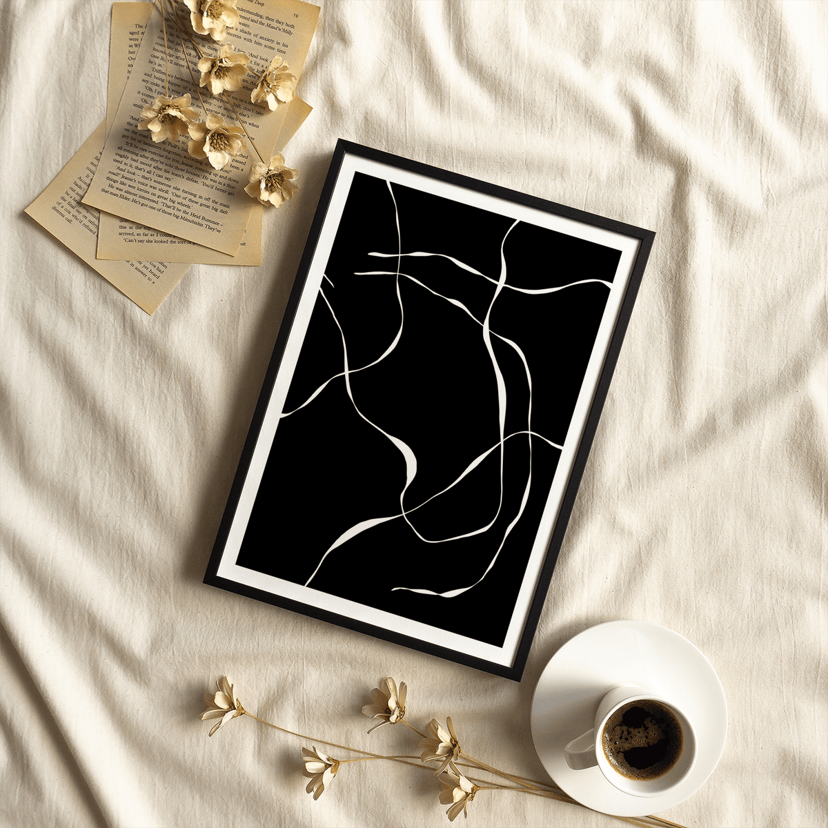 Abstract Lines Art Print with white abstract lines on black background framed in black surrounded by dried flowers and a cup of coffee