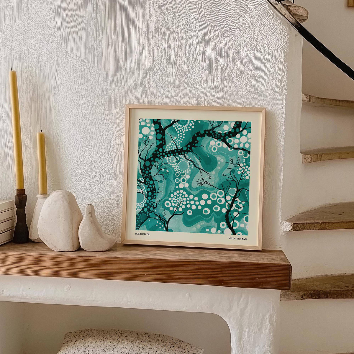 Print leaning on a shelf with abstract tree branches and teal and white colours with decorative candles nearby
