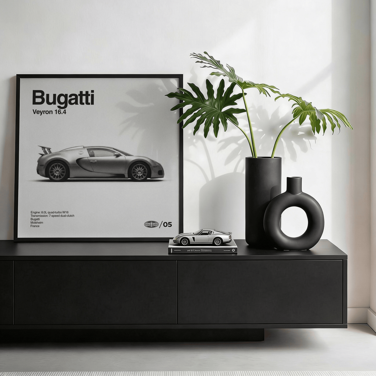 Hypercar wall art leaning on a black sideboard beside a round black vase with green leaves