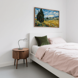 Nature poster of a field with cypress trees and swirling blue sky above a bed with a green cushion