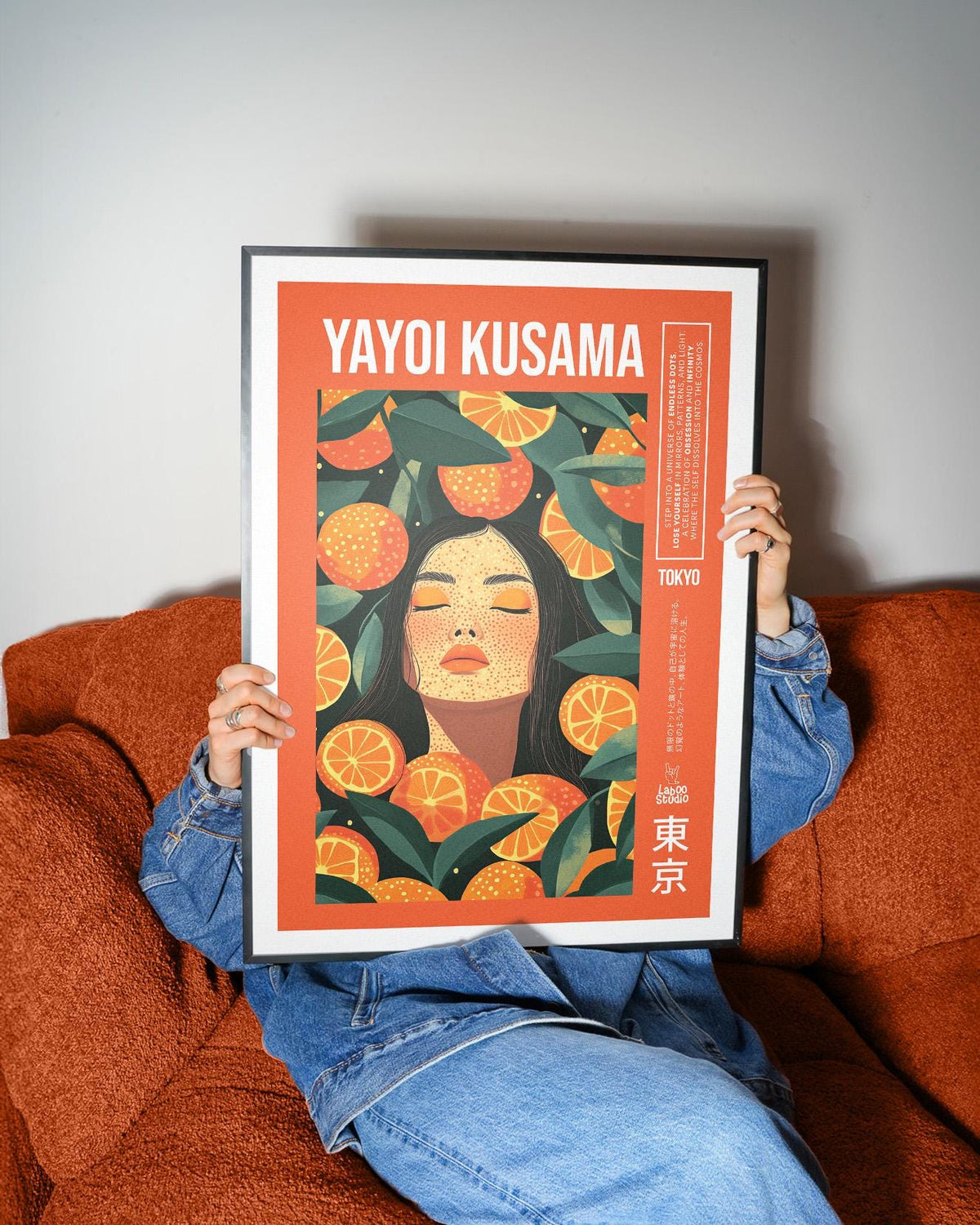 Cool wall art held by person on orange sofa shows woman with orange slices and green leaves
